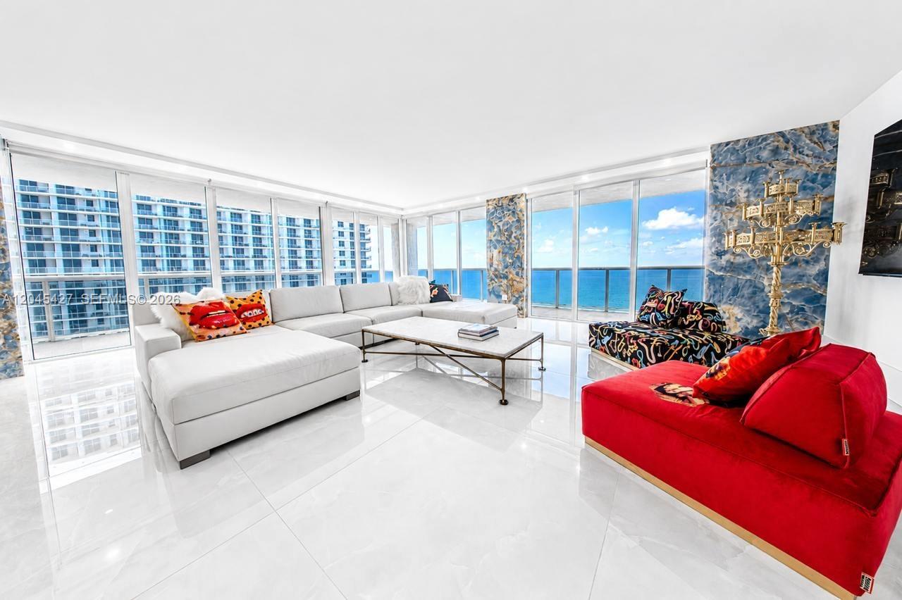 A bright living room features white tile floors, a large sectional, and floor-to-ceiling ocean views — 1800 S Ocean Dr # 3601, Hallandale Beach FL 33009, HALLANDALE BEACH, FL