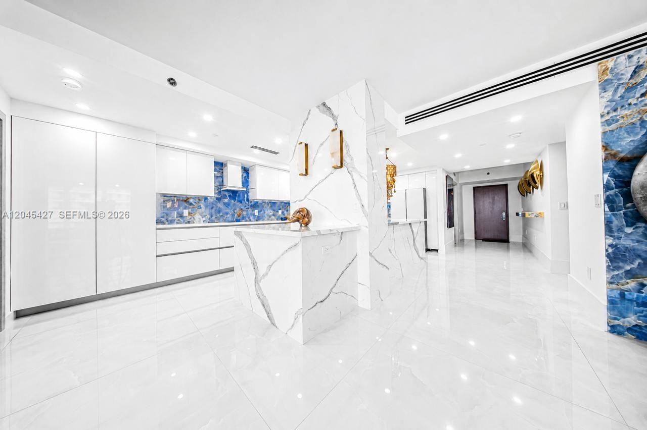 A modern kitchen features white marble surfaces, blue stone backsplashes, and high-gloss cabinetry — 1800 S Ocean Dr # 3601, Hallandale Beach FL 33009, HALLANDALE BEACH, FL