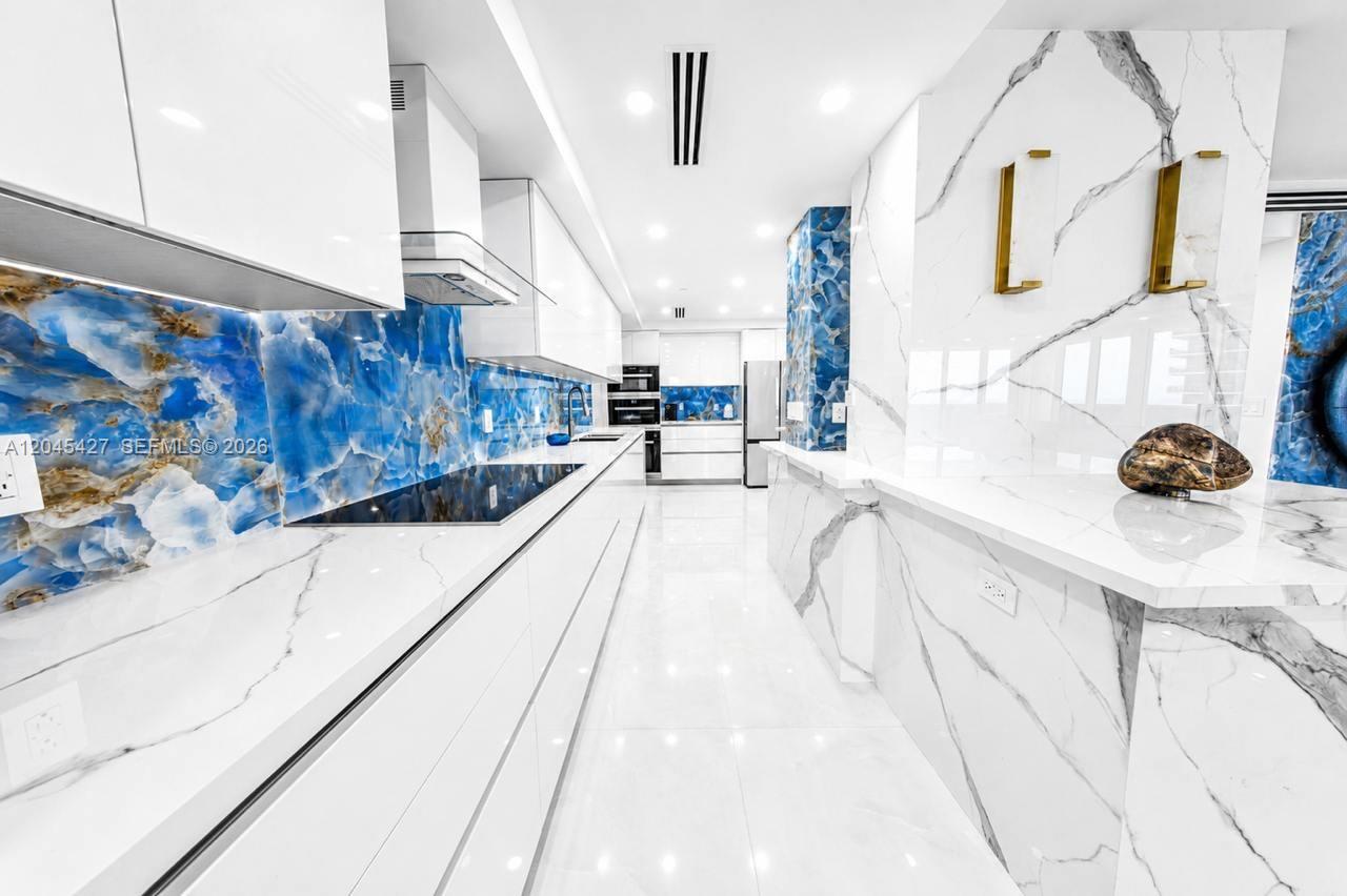 A modern kitchen features white marble countertops, glossy white cabinets, and blue agate backsplashes — 1800 S Ocean Dr # 3601, Hallandale Beach FL 33009, HALLANDALE BEACH, FL