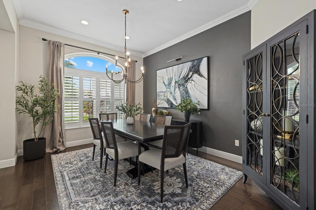 A dining room features a dark wood table, upholstered chairs, a patterned rug, and gray walls — 7574 TORI WAY, BRADENTON, FL