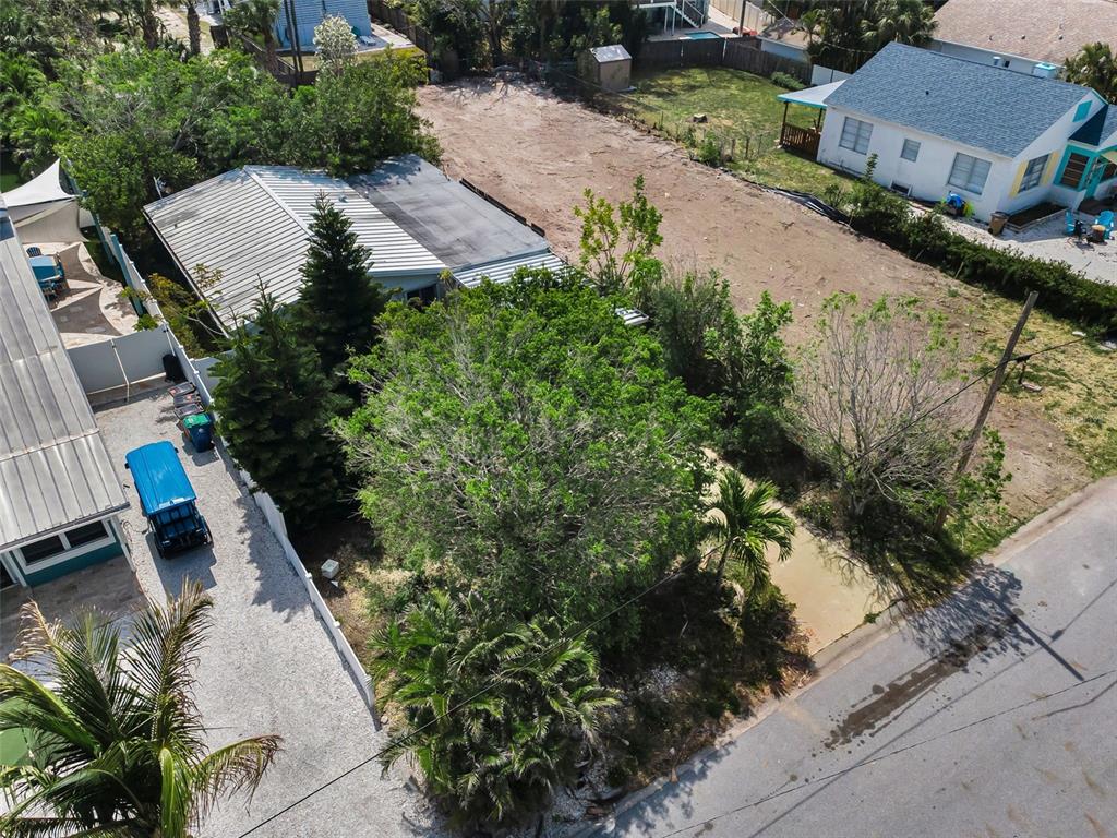 An aerial view shows a residential lot with a house, trees, and a gravel driveway — 1213 BAY PALM BOULEVARD, INDIAN ROCKS BEACH, FL