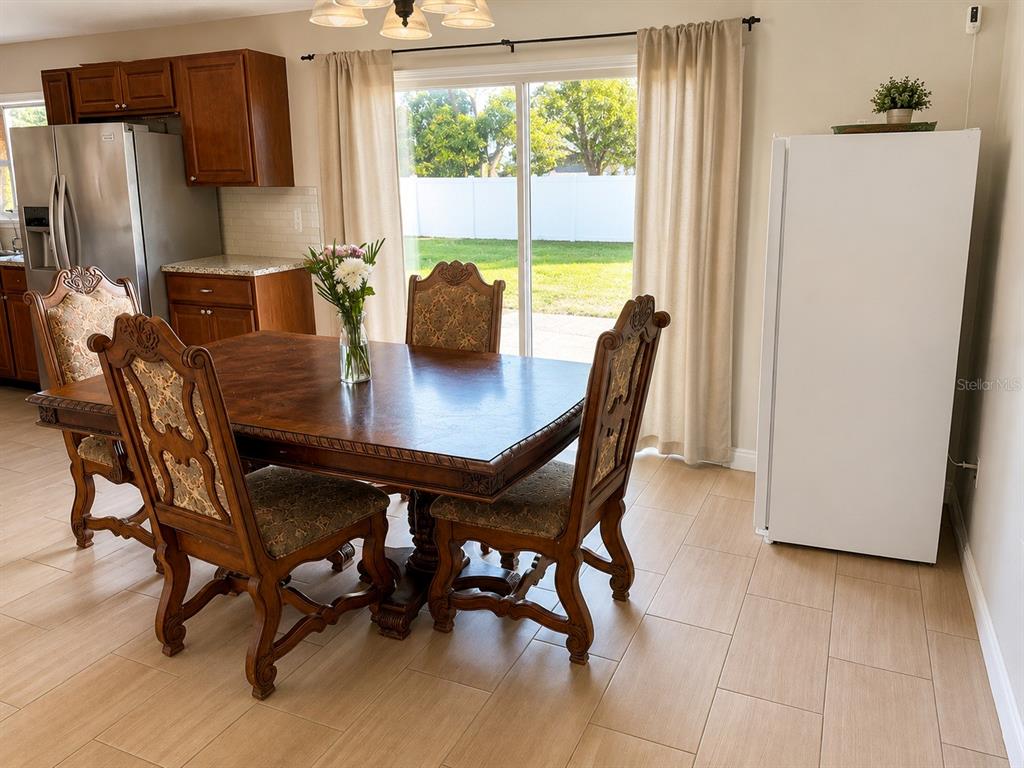 A dining area features a wooden table, ornate chairs, tile flooring, and a sliding glass door — 1540 JUPITER AVENUE, DELTONA, FL