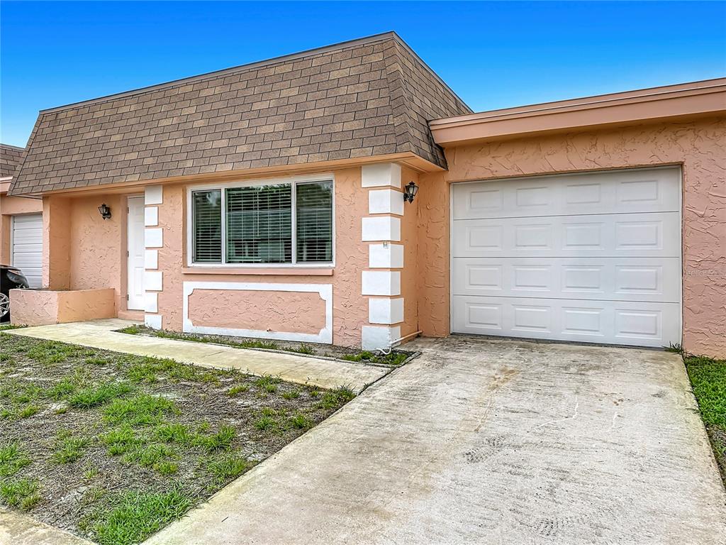 A single-story peach-colored house features a brown mansard roof, white trim, and a garage — 8454 AUSTIN N, PINELLAS PARK, FL