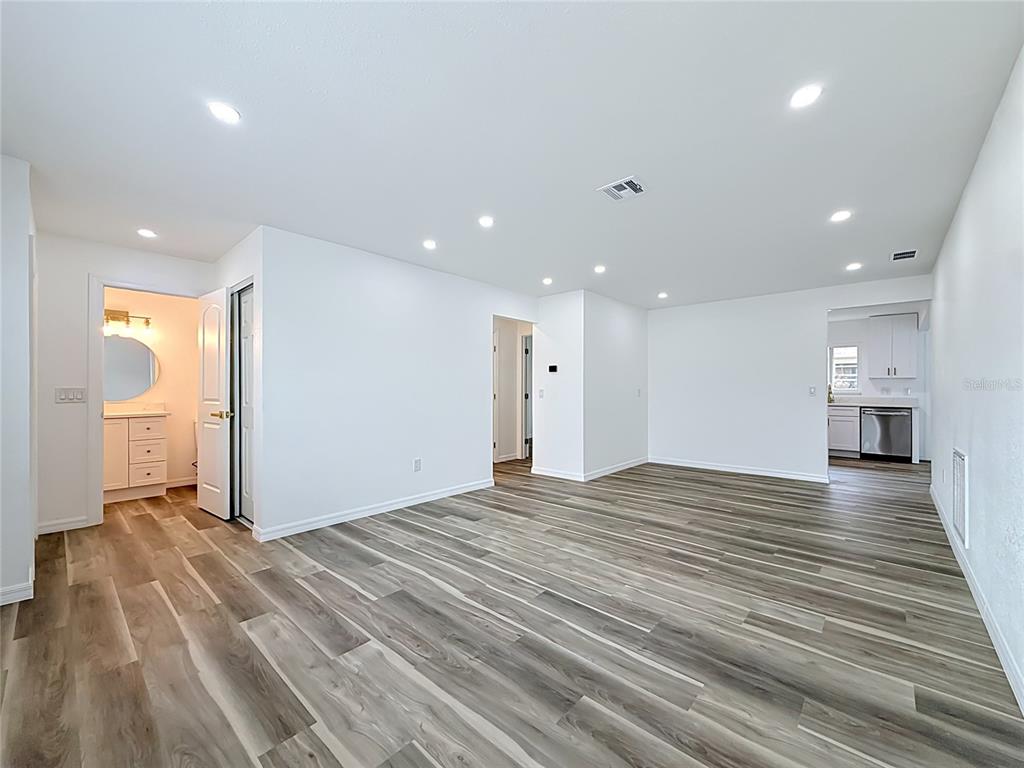 An empty room with light-colored walls, recessed lighting, and wood-look vinyl plank flooring — 8454 AUSTIN N, PINELLAS PARK, FL