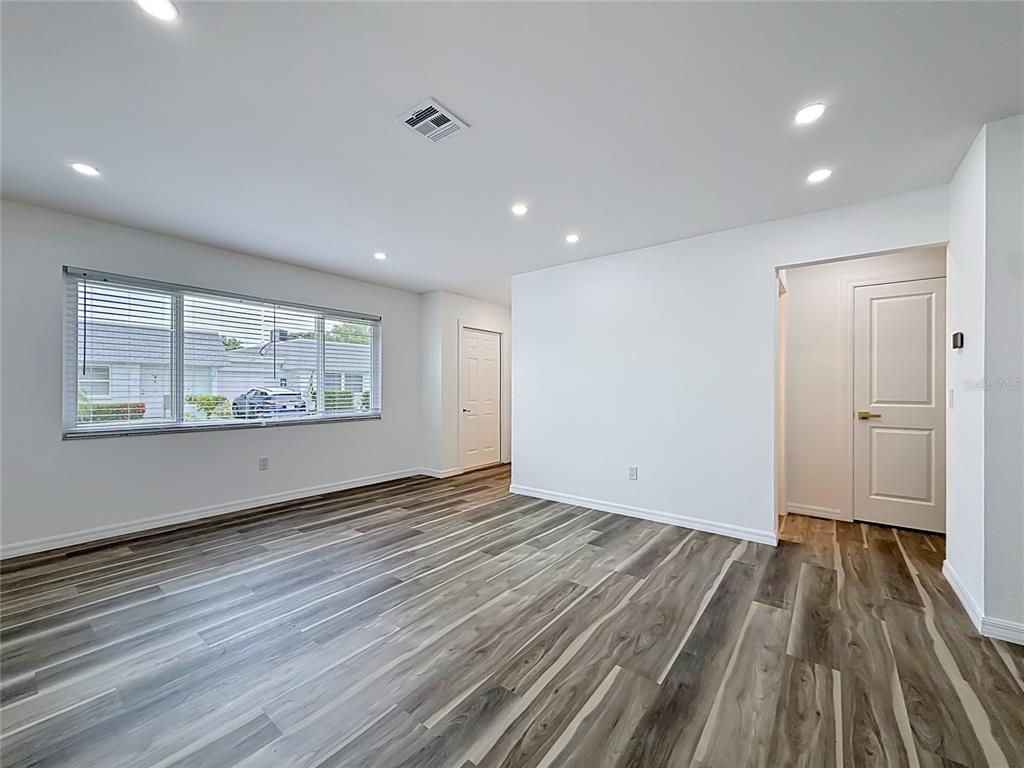 An empty room features white walls, recessed lighting, and wood-look flooring with a large window — 8454 AUSTIN N, PINELLAS PARK, FL