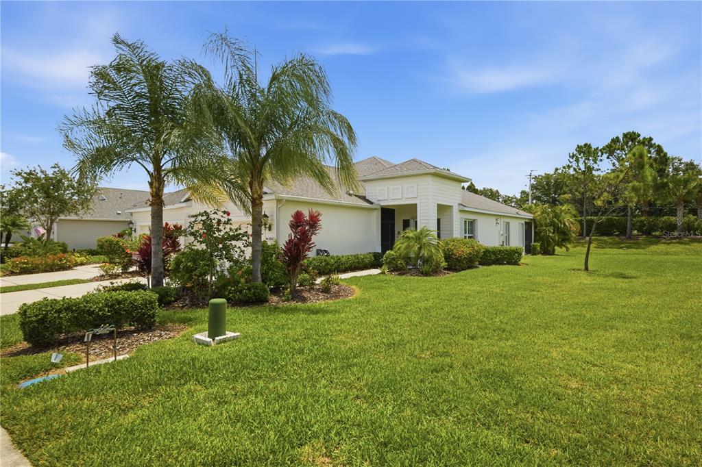 A single-story house with a light-colored exterior, palm trees, and a manicured lawn — 4504 DEEP CREEK TERRACE, PARRISH, FL