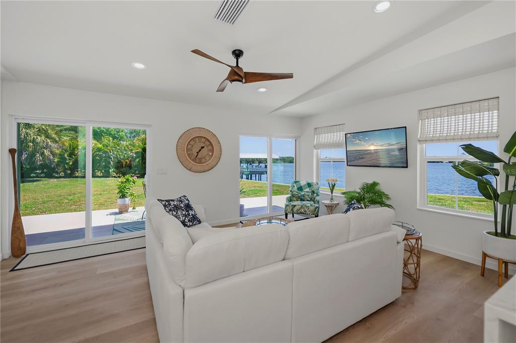 A bright living room features a white sofa, a ceiling fan, and views of water — 3404 LAKE VIEW BOULEVARD, PORT CHARLOTTE, FL