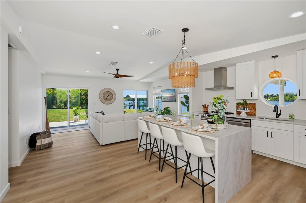 A bright open-concept kitchen and living area features a marble-topped island and waterfront views — 3404 LAKE VIEW BOULEVARD, PORT CHARLOTTE, FL