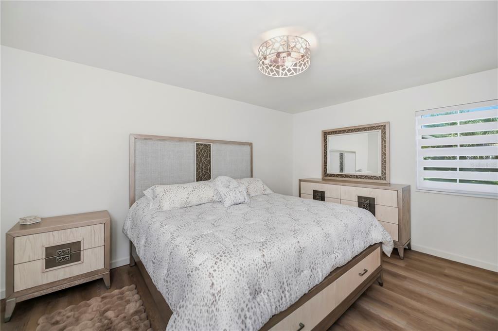 A bedroom features a bed with a patterned comforter, matching furniture, and a ceiling light — 3404 LAKE VIEW BOULEVARD, PORT CHARLOTTE, FL