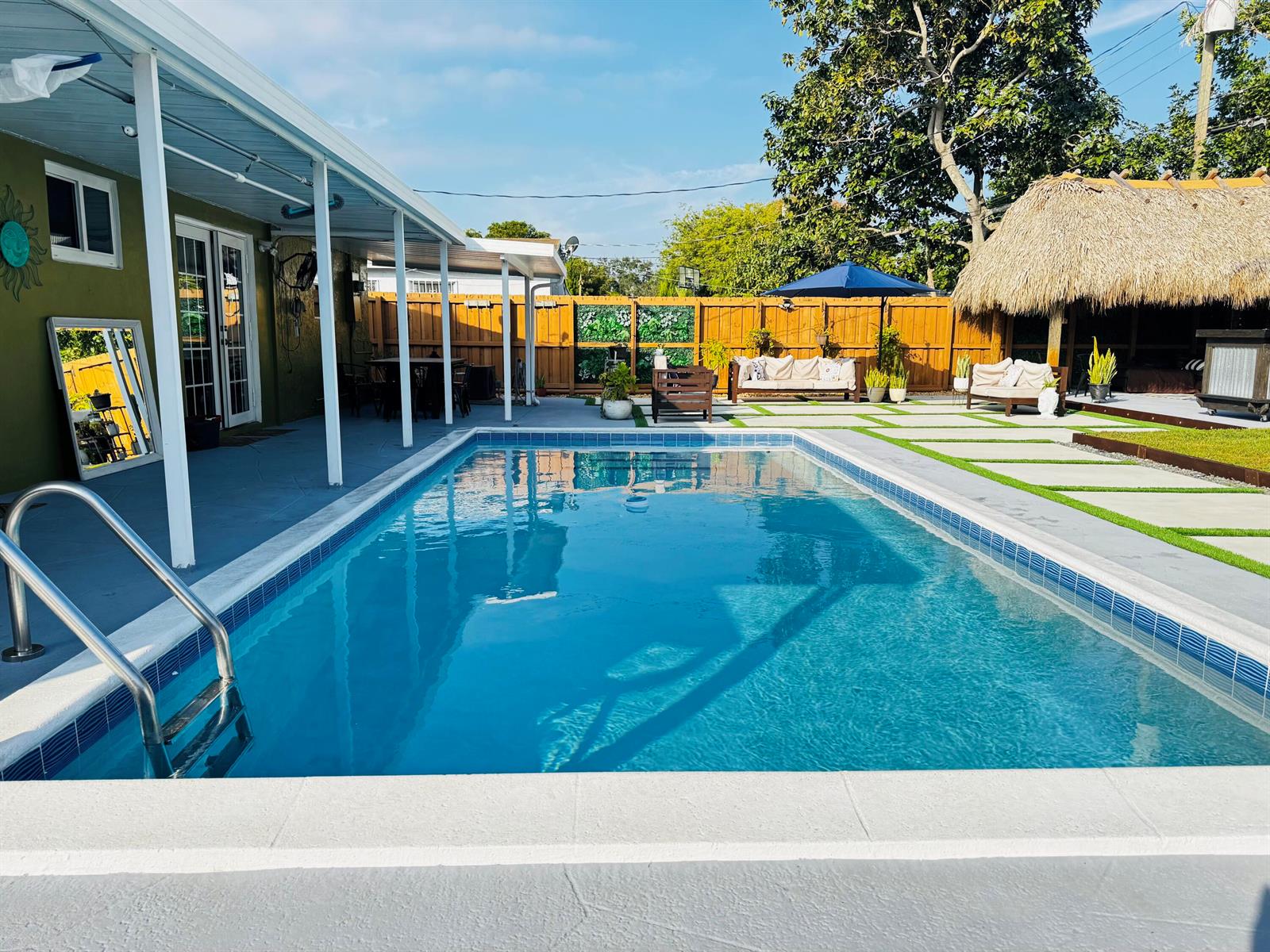 A backyard swimming pool with a patio, outdoor seating, and a thatched-roof tiki bar — 7161 Sheridan Street, Hollywood FL 33024, HOLLYWOOD, FL