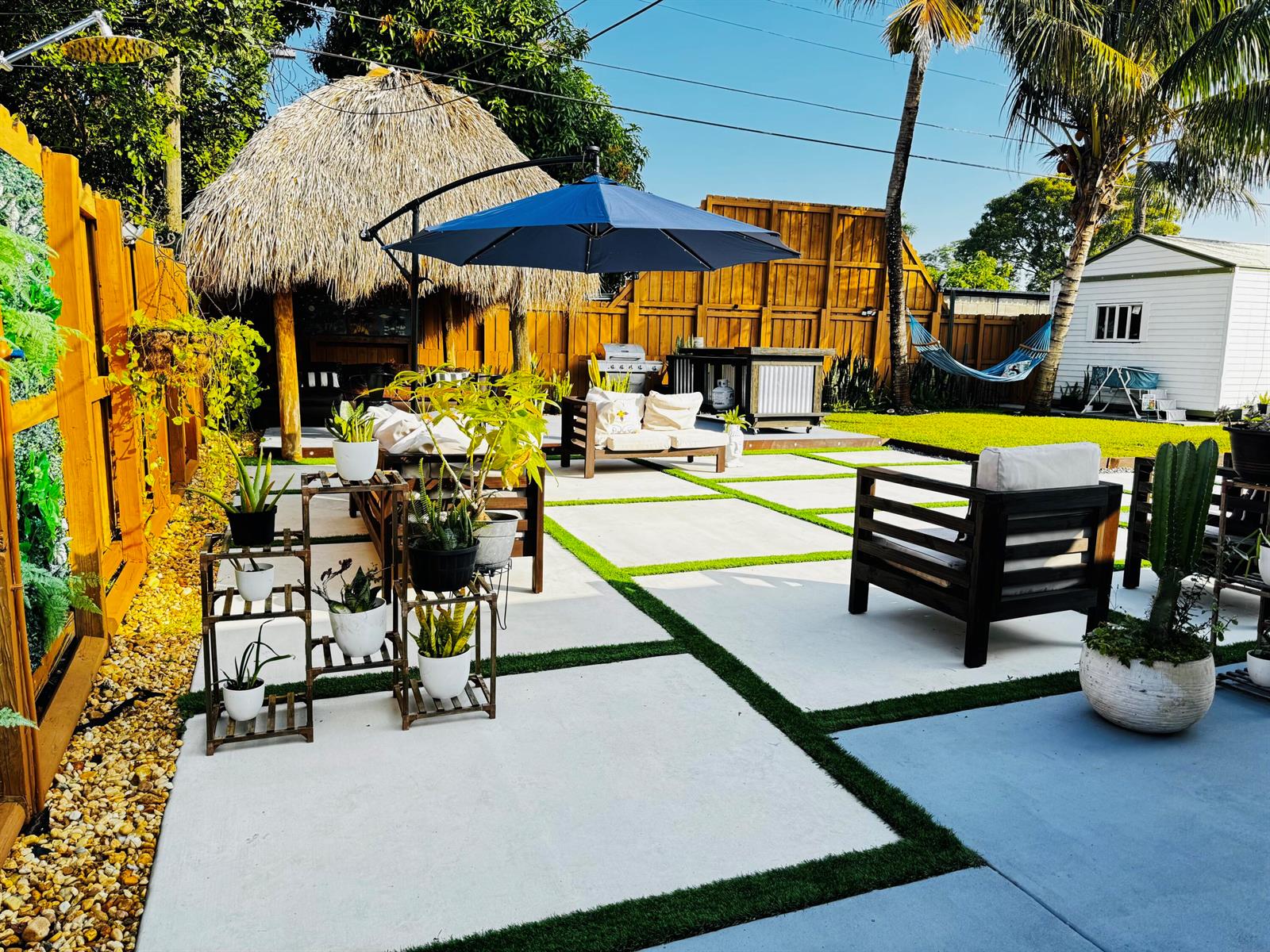 A backyard patio features concrete pavers with grass borders, a tiki hut, and outdoor furniture — 7161 Sheridan Street, Hollywood FL 33024, HOLLYWOOD, FL
