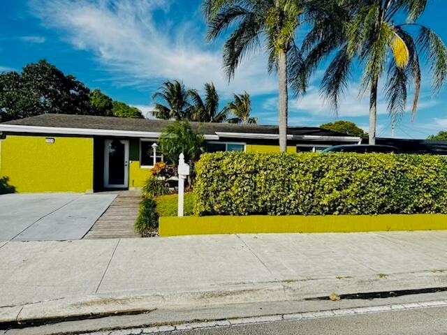 A single-story house with bright yellow exterior walls and a tall green hedge in front — 7161 Sheridan Street, Hollywood FL 33024, HOLLYWOOD, FL
