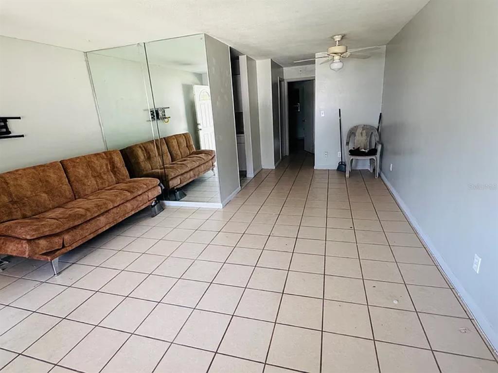 A living room features light-colored floor tiles, a brown sofa, and a large mirrored wall — 2353 SHELLEY STREET UNIT 11, CLEARWATER, FL