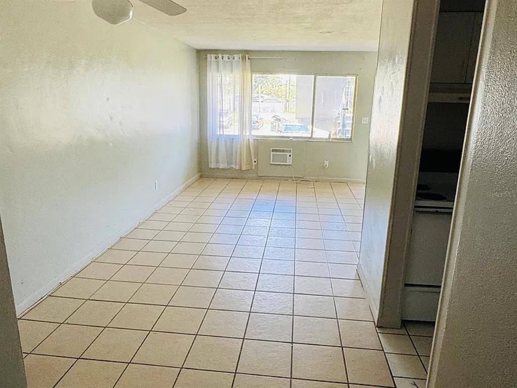 An empty room with light-colored tile flooring, a ceiling fan, and a large window — 2353 SHELLEY STREET UNIT 11, CLEARWATER, FL
