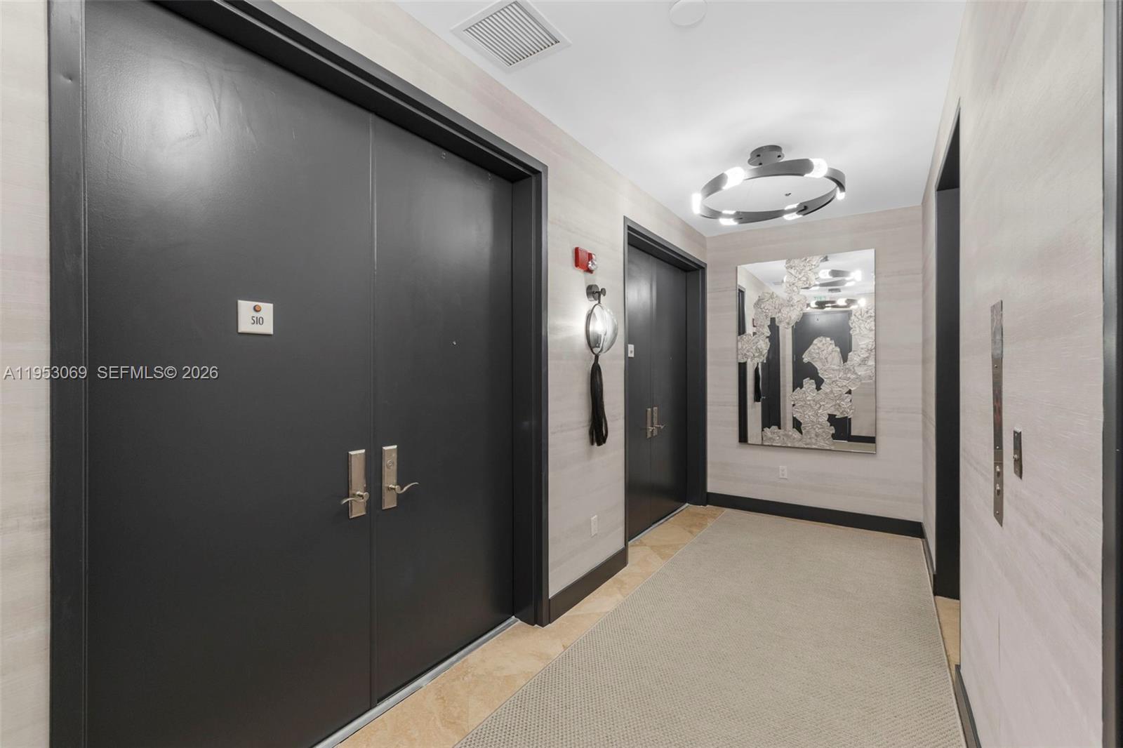 A hallway features two dark double doors, a modern circular light fixture, and textured wallpaper — 100 S Pointe Dr # 510, Miami Beach FL 33139, MIAMI BEACH, FL