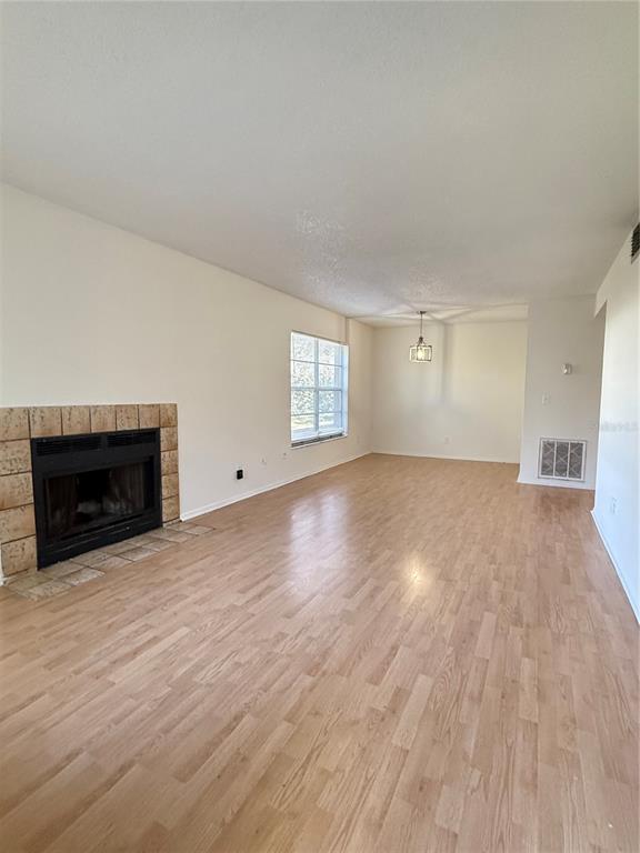 A living room with light wood-look flooring, a tiled fireplace, and a dining area — 14308 HANGING MOSS CIRCLE UNIT 102, TAMPA, FL