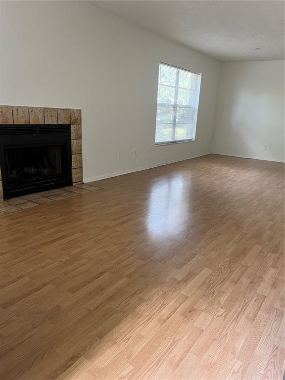 A living room features light wood-look flooring, white walls, and a tiled fireplace — 14308 HANGING MOSS CIRCLE UNIT 102, TAMPA, FL