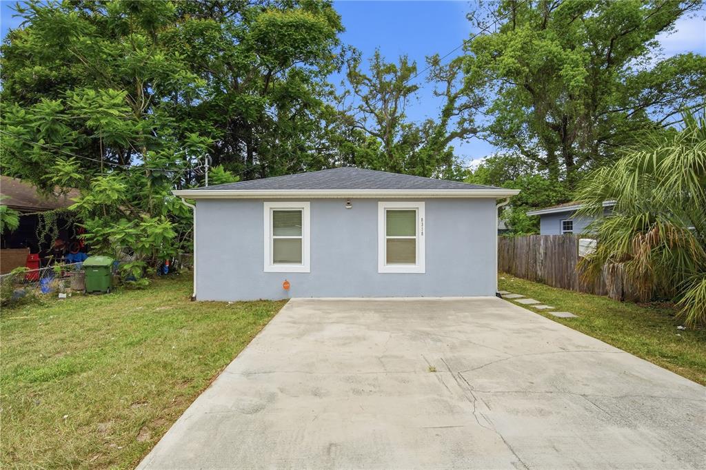 A single-story house with light blue siding, a concrete driveway, and two front windows — 8310 N BROOKS STREET, TAMPA, FL