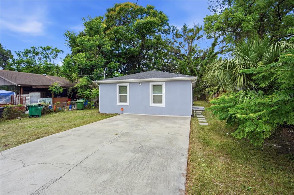 A light blue single-story house features a concrete driveway and two windows on the front — 8310 N BROOKS STREET, TAMPA, FL