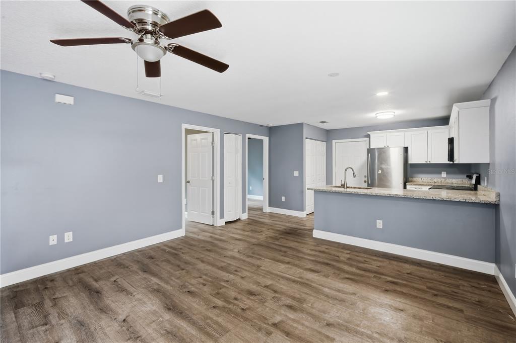 An open-concept living area features light blue walls, wood-look flooring, and a kitchen with granite countertops — 8310 N BROOKS STREET, TAMPA, FL