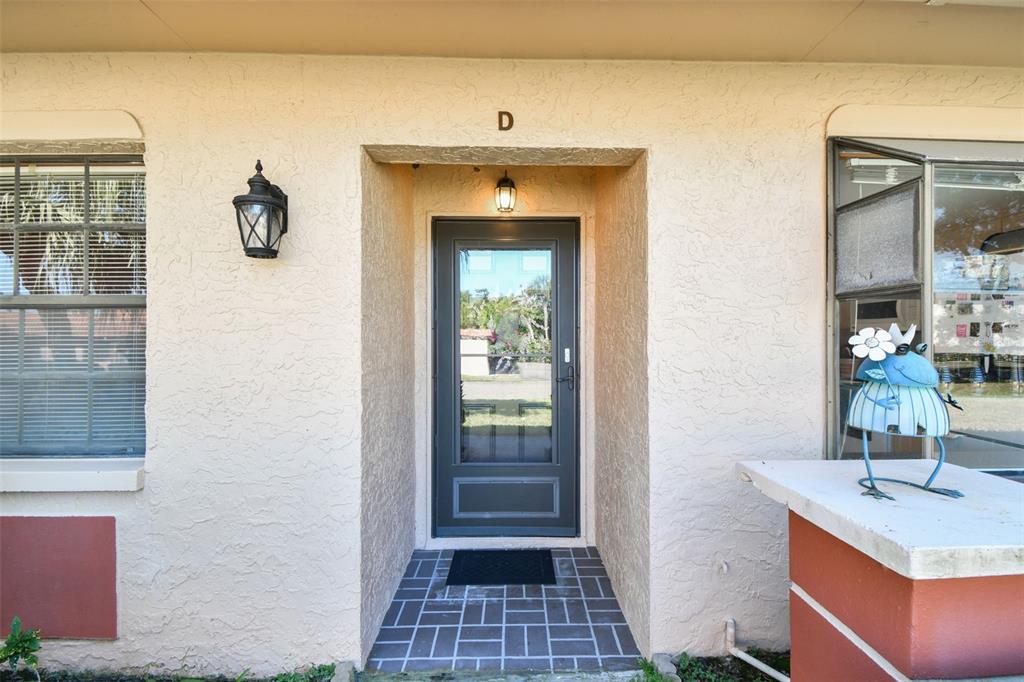 An exterior view of a residential unit entrance labeled D with a dark storm door — 19029 US HIGHWAY 19 N UNIT 10D, CLEARWATER, FL