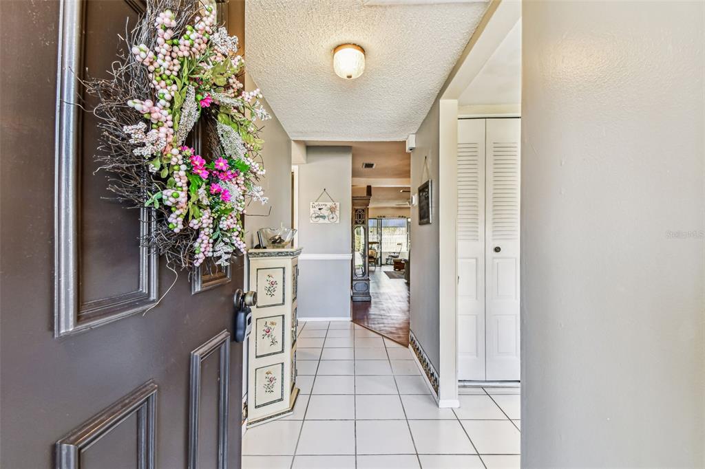 A view from an open front door into a tiled entryway with a decorative cabinet — 19029 US HIGHWAY 19 N UNIT 10D, CLEARWATER, FL