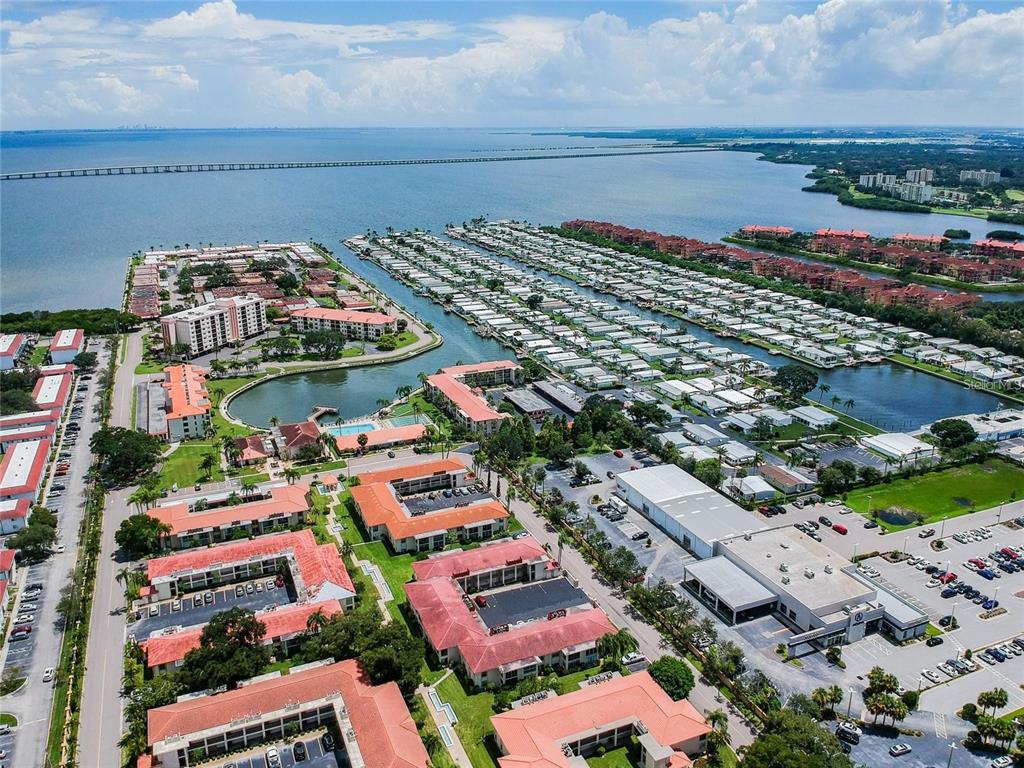 An aerial view shows a waterfront residential complex with multiple buildings, parking lots, and docks — 19029 US HIGHWAY 19 N UNIT 10D, CLEARWATER, FL