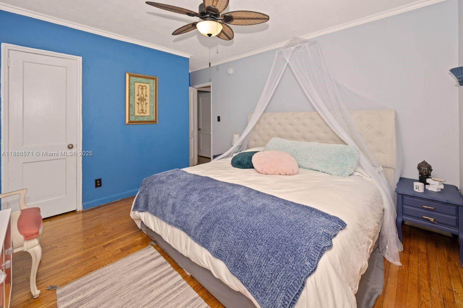 A bedroom features a tufted headboard, a canopy, a blue accent wall, and wood flooring — 1701 Fletcher St, Hollywood FL 33020, HOLLYWOOD, FL