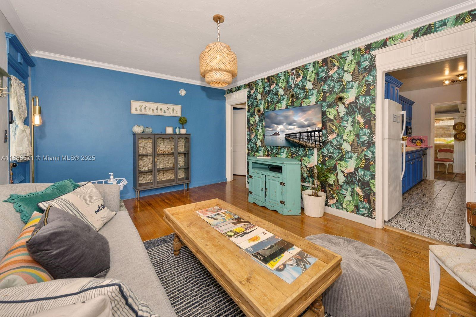 A living room features blue walls, tropical wallpaper, a wooden coffee table, and hardwood floors — 1701 Fletcher St, Hollywood FL 33020, HOLLYWOOD, FL