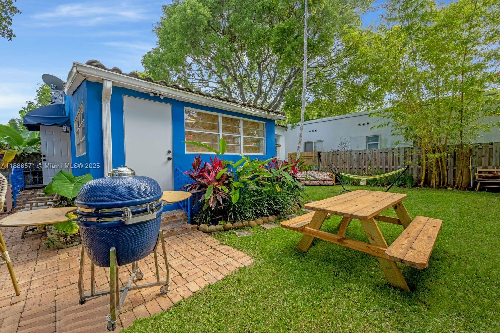 A blue house exterior features a brick patio, a charcoal grill, and a wooden picnic table — 1701 Fletcher St, Hollywood FL 33020, HOLLYWOOD, FL
