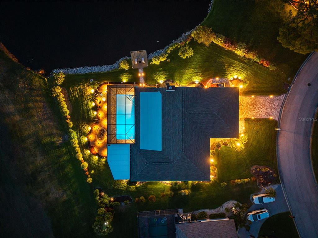 An aerial night view shows a house with a pool, deck, and waterfront backyard — 3615 AVENIDA MADERA, BRADENTON, FL