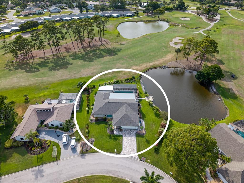 An aerial view shows a single-story house with a pool cage beside a golf course — 3615 AVENIDA MADERA, BRADENTON, FL