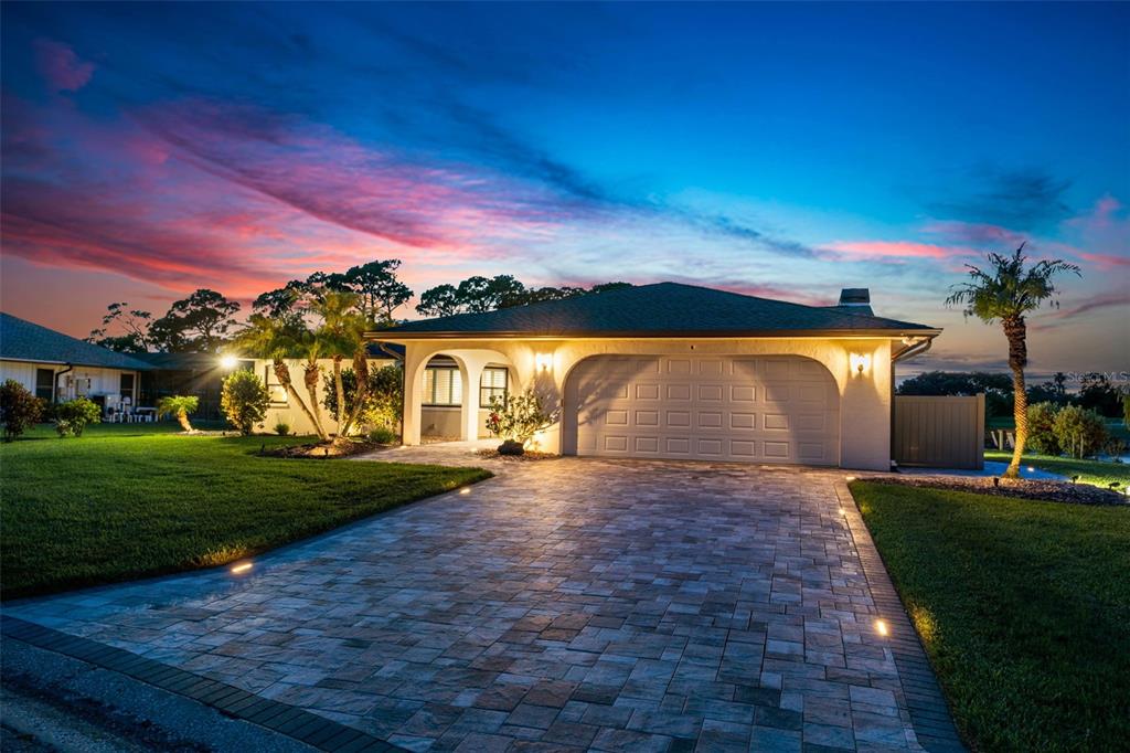 A single-story house with a paved driveway and a two-car garage at sunset — 3615 AVENIDA MADERA, BRADENTON, FL