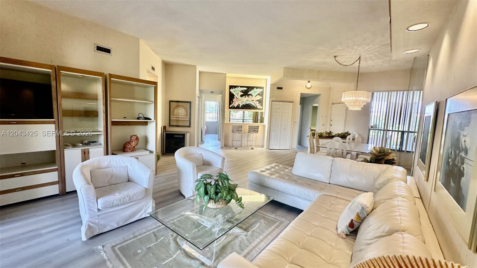 A bright living room features white leather furniture, a glass coffee table, and light flooring — 7472 La Paz Blvd # 301, Boca Raton FL 33433, BOCA RATON, FL