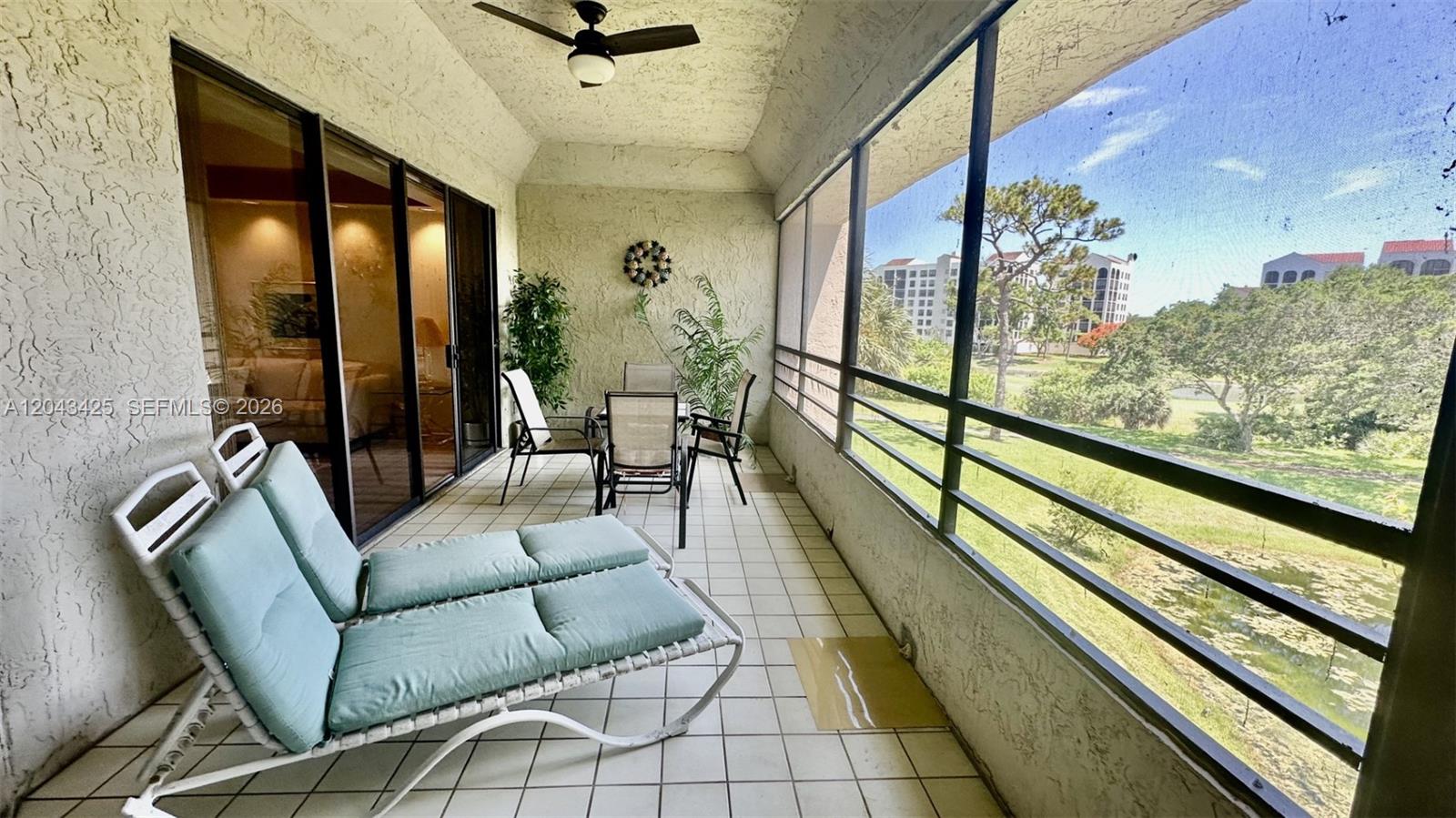 A screened-in balcony features tiled flooring, patio furniture, and a view of a grassy area — 7472 La Paz Blvd # 301, Boca Raton FL 33433, BOCA RATON, FL