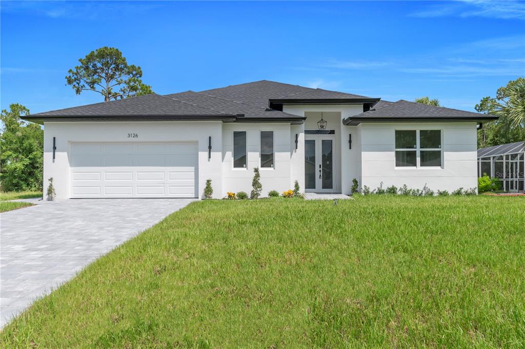 A modern, white, single-story house with a dark roof and a paved driveway — 3126 BELLEVILLE TER, NORTH PORT, FL