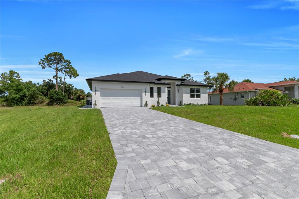 A modern single-story house with a white exterior, dark roof, and a paved driveway — 3126 BELLEVILLE TER, NORTH PORT, FL