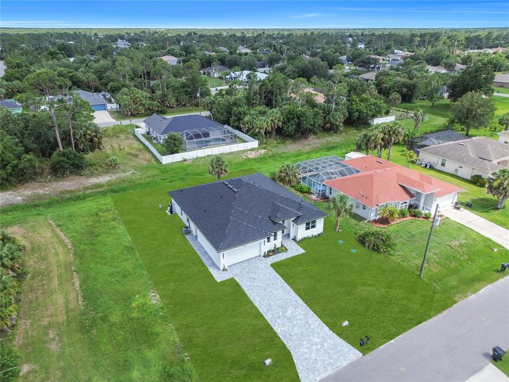 An aerial view shows a single-story house with a dark roof and paved driveway — 3126 BELLEVILLE TER, NORTH PORT, FL