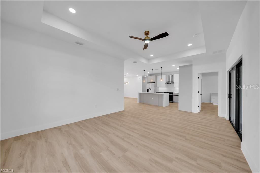 An open-concept living area features light wood flooring, a tray ceiling, and a kitchen island — 3126 BELLEVILLE TER, NORTH PORT, FL