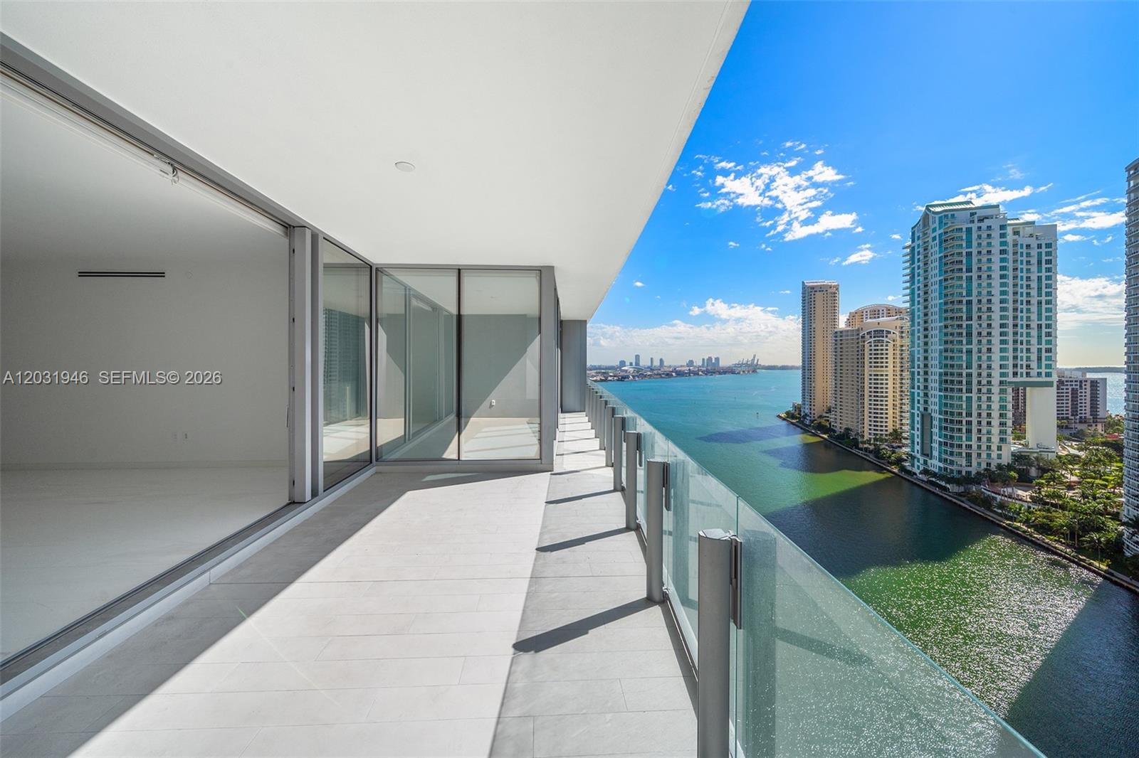 A balcony with glass railings overlooks a bay and city skyline — 300 Biscayne Blvd Way # 1904C, Miami FL 33131, MIAMI, FL