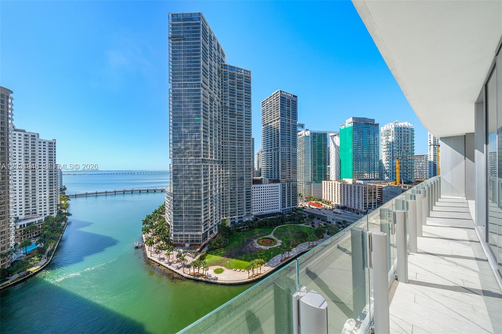 A balcony view overlooking a waterfront park and high-rise buildings in a city — 300 Biscayne Blvd Way # 1904C, Miami FL 33131, MIAMI, FL