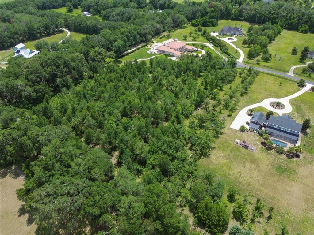 An aerial view shows a large wooded area surrounded by several houses and driveways — 4023 NW 155TH TERRACE, NEWBERRY, FL