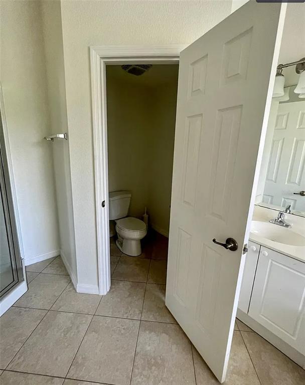 A bathroom features a tiled floor, a vanity with a sink, and a separate toilet closet — 2884 CLUB CORTILE CIRCLE, KISSIMMEE, FL