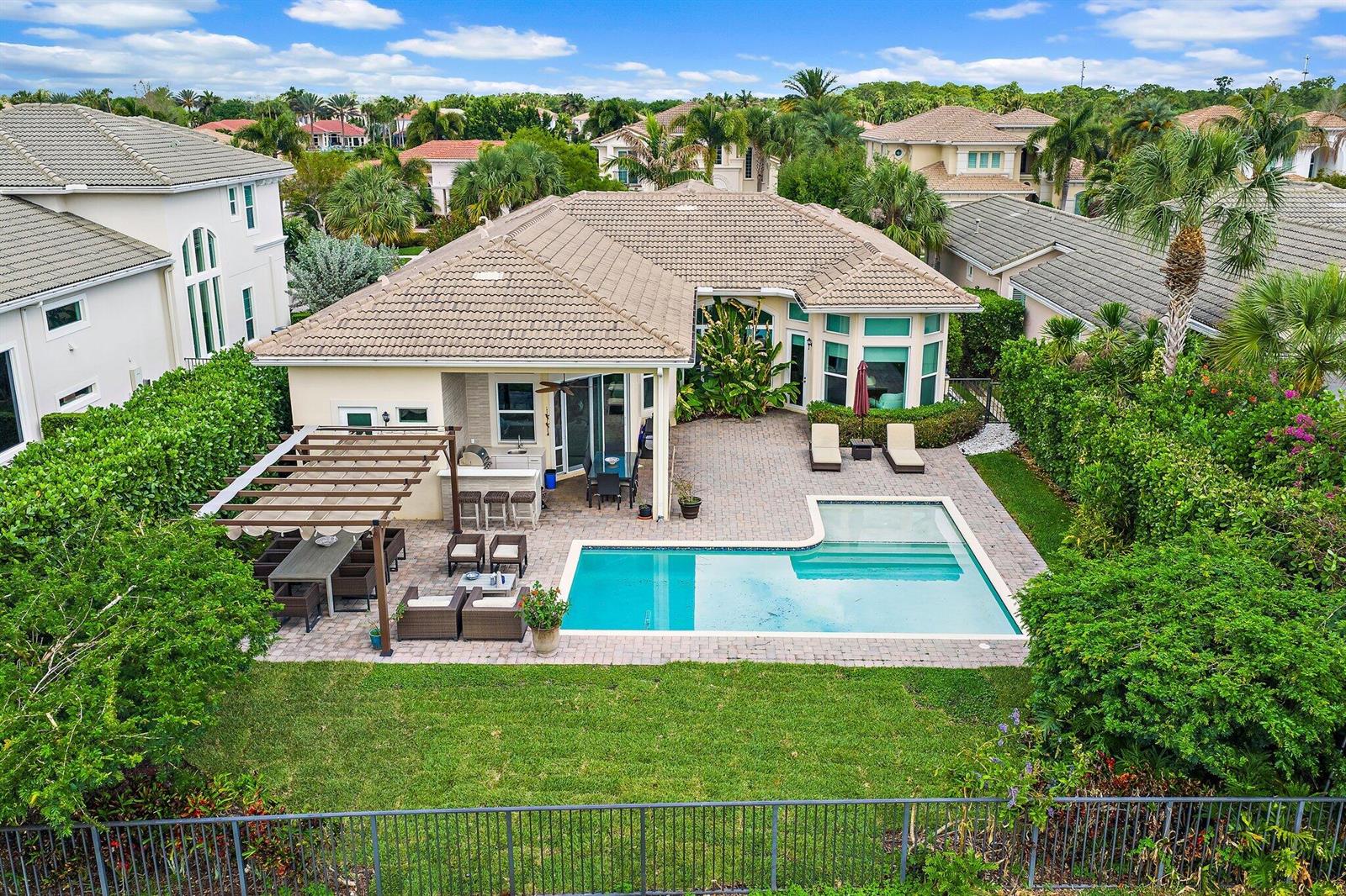 An aerial view of a house backyard featuring a swimming pool, patio, and pergola — 114 Carmela Court, Jupiter FL 33478, JUPITER, FL