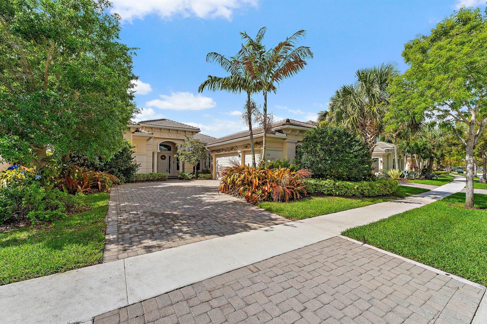 A single-story house with a paved driveway, palm trees, and landscaping under a blue sky — 114 Carmela Court, Jupiter FL 33478, JUPITER, FL