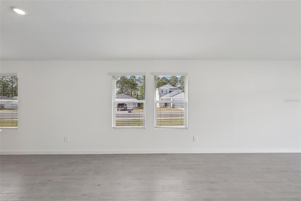 A room with white walls, gray tile flooring, and three windows looking out at houses — 106 WANDERING CREEK WAY, PALM COAST, FL