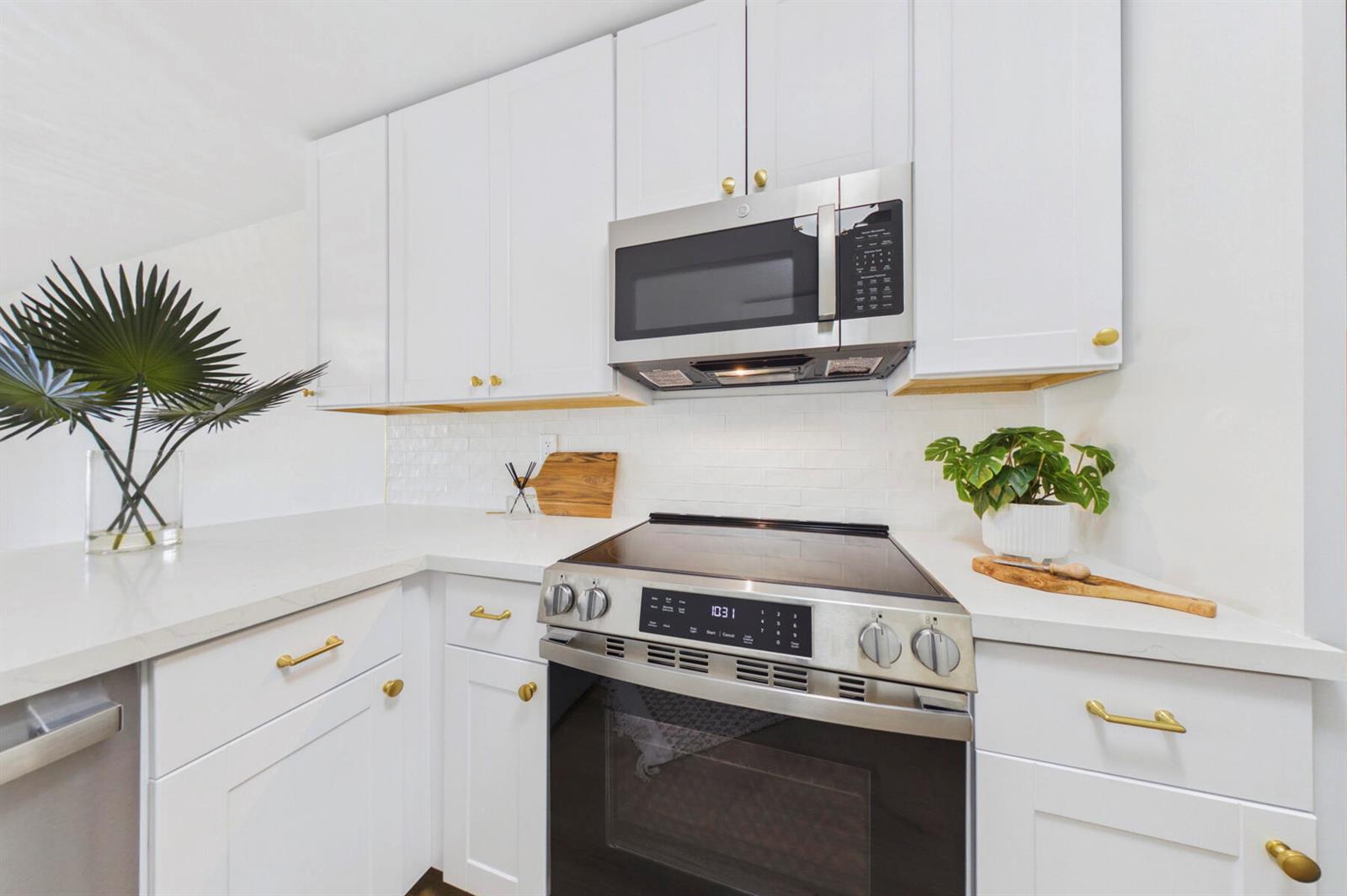 A kitchen features white cabinets, gold hardware, stainless steel appliances, and a white subway tile backsplash — 262 Timberwalk Trail, Jupiter FL 33458, JUPITER, FL