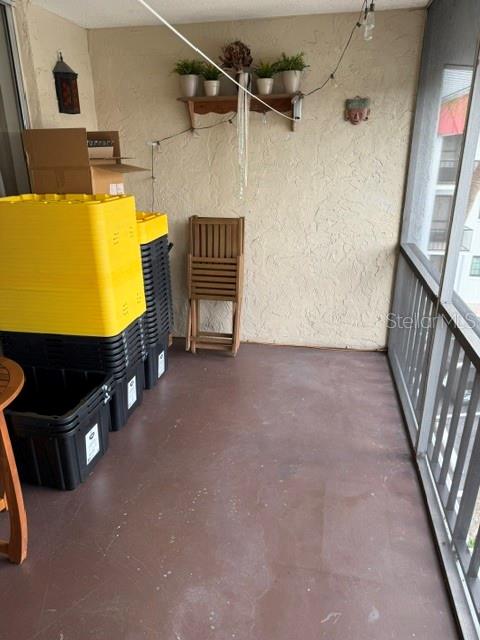 A covered balcony features a concrete floor, a stack of plastic storage bins, and a wooden chair — 10530 77TH TERRACE UNIT 323, SEMINOLE, FL