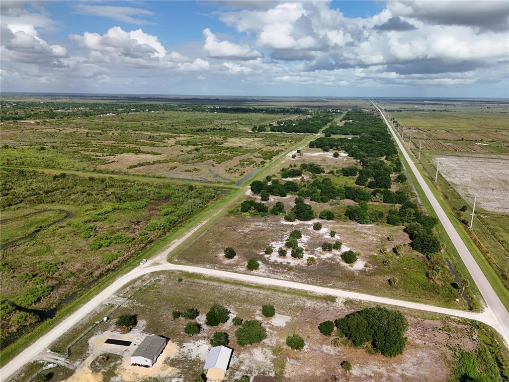 An aerial view shows a rural landscape with a road, sparse trees, and a house — 16734 NW 242ND STREET, OKEECHOBEE, FL