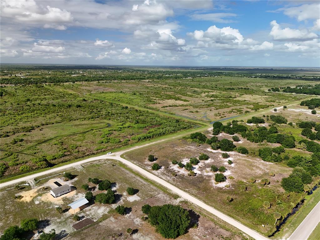 An aerial view shows a rural landscape with a house, dirt roads, and vegetation — 16734 NW 242ND STREET, OKEECHOBEE, FL